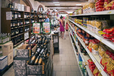 Supermercado en hu Norcenni Girasole Village, Toscana, Italia, con vino, pasta y clientes comprando.
