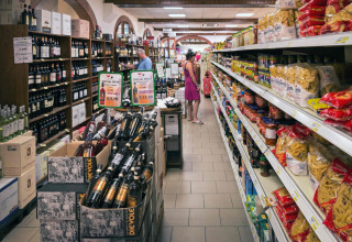 Supermarché au hu Norcenni Girasole Village, Toscane, Italie, avec vin, pâtes et clients dans les rayons.