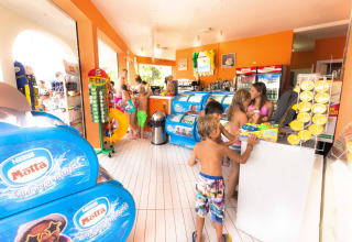 Kinderen in zwemkleding kopen ijsjes en snacks bij hu Norcenni Girasole Village vakantiepark in Toscane, Italië.