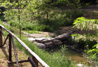Scenic stream and rustic bridge surrounded by greenery at hu Norcenni Girasole Village in Tuscany, Italy.