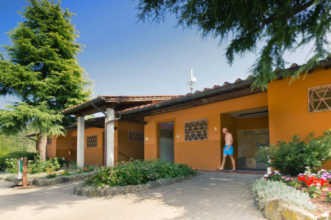 Outdoor view of hu Norcenni Girasole Village holiday park in Tuscany, Italy, with a man in swim trunks.