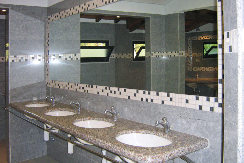 Modern public restroom with four sinks, granite countertop and large mirrors at Norcenni Girasole Village, Tuscany.