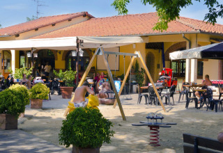 Buitencafé en speeltuin in een vakantiepark in Toscane, Italië, gezinnen ontspannen samen.