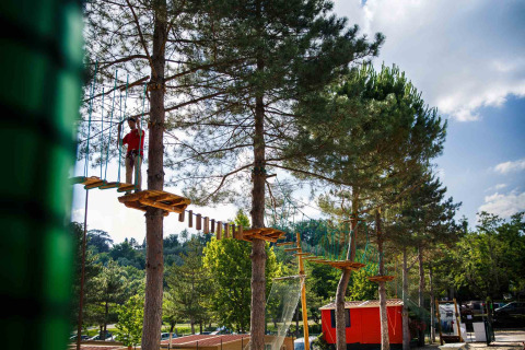 Persona en un circuito de cuerdas entre árboles en hu Norcenni Girasole Village, Toscana, Italia.