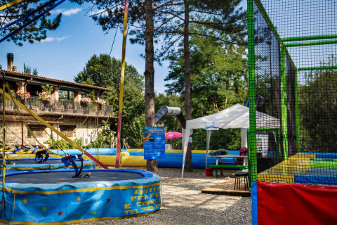 Buitenspeeltuin met trampolines en tenten in hu Norcenni Girasole Village, vakantiepark in Toscane, Italië.