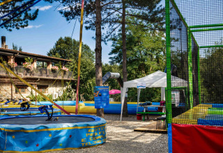Buitenspeeltuin met trampolines en tenten in hu Norcenni Girasole Village, vakantiepark in Toscane, Italië.