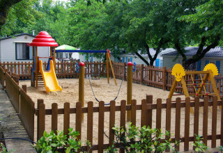 Parco giochi recintato con scivolo e altalene al villaggio hu Norcenni Girasole, Toscana, Italia.