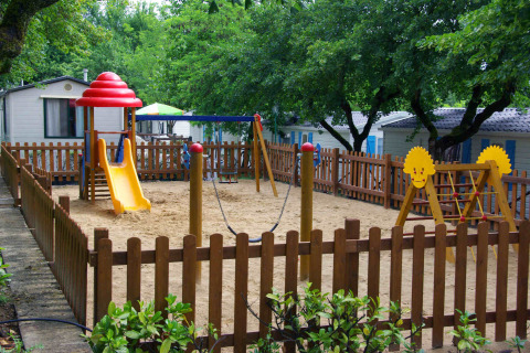 Fenced playground with slide and swings at the holiday park hu Norcenni Girasole Village, Tuscany, Italy.
