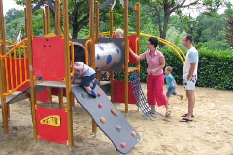 Niños juegan en un parque infantil con pared de escalada y tobogán en un resort de vacaciones en la Toscana, Italia.