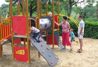 Bambini giocano in un parco giochi con parete da arrampicata e scivolo in un villaggio vacanze in Toscana, Italia.