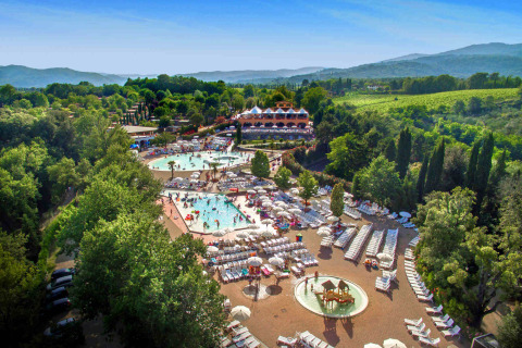 Luchtzicht op Norcenni Girasole Village in Toscane met zwembaden, ligzetels en veel groen.
