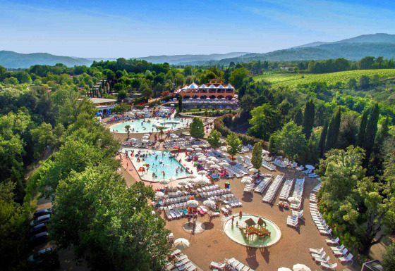 Veduta aerea del villaggio Norcenni Girasole in Toscana con piscine, lettini e vegetazione lussureggiante.