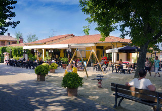Buitenterras en speeltuin met mensen bij hu Norcenni Girasole Village vakantiepark in Toscane, Italië.