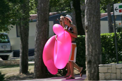 Due persone camminano con un gonfiabile rosa al Camping Village Mare Pineta, Friuli-Venezia Giulia, Italia.