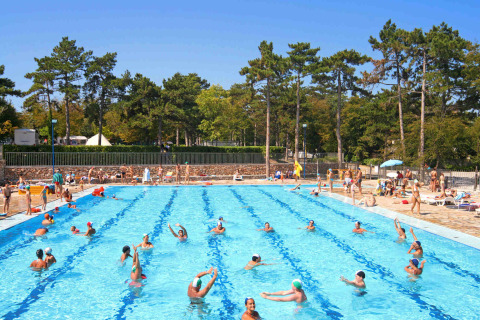 Piscina all’aperto al Camping Village Mare Pineta con turisti che nuotano e si rilassano tra i pini in Italia.