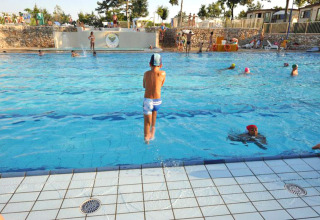 Children playing and swimming in the outdoor pool at Camping Village Mare Pineta in Friuli-Venezia Giulia, Italy.