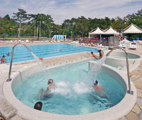 Zona de piscinas del Camping Village Mare Pineta en Friuli-Venezia Giulia, Italia, con personas y tumbonas.