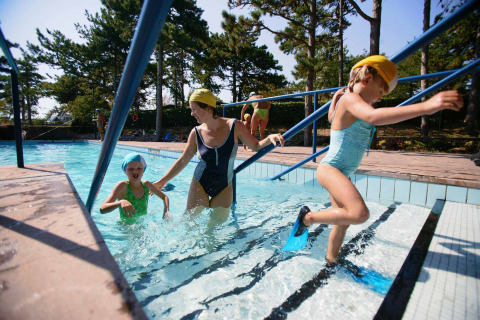 Bambini e adulto con costumi e pinne in piscina al Camping Village Mare Pineta, Friuli-Venezia Giulia, Italia.