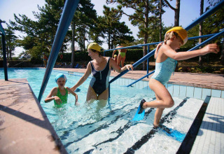 Bambini e adulto con costumi e pinne in piscina al Camping Village Mare Pineta, Friuli-Venezia Giulia, Italia.