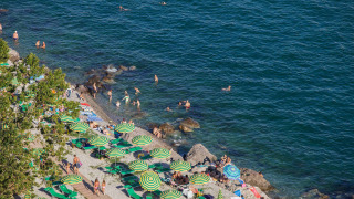 Playa con sombrillas verdes y amarillas en Camping Village Mare Pineta, Friuli-Venezia Giulia, Italia.