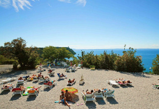 People sunbathing on lounge chairs at Camping Village Mare Pineta overlooking the sea in Friuli-Venezia Giulia, Italy.