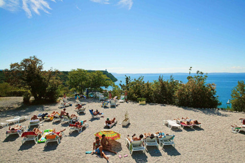 Zonnebaders relaxen op ligstoelen bij Camping Village Mare Pineta met zeezicht in Friuli-Venezia Giulia, Italië.