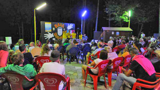 Espectáculo nocturno en Camping Village Mare Pineta, Friuli-Venezia Giulia, Italia, con público en sillas.