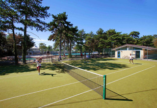 Campi da tennis al Camping Village Mare Pineta, Friuli-Venezia Giulia, Italia, con ospiti che giocano.