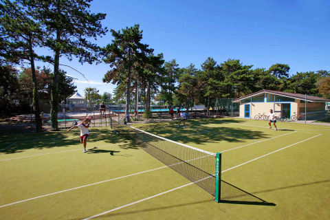 Tennisvelden bij Camping Village Mare Pineta in Friuli-Venezia Giulia, Italië, met spelende gasten.