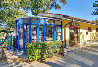 Supermarkedet Despar-indgang ved Camping Village Mare Pineta i Friuli-Venezia Giulia, Italien, omgivet af grønne træer.