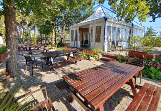 Outdoor dining area with wooden tables at Camping Village Mare Pineta, Friuli-Venezia Giulia, Italy.