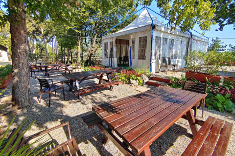 Buitenterras met houten banken en tafels bij Camping Village Mare Pineta, Friuli-Venezia Giulia, Italië.