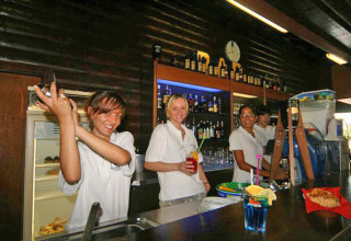 Bartendere forbereder farverige drinks bag baren på Camping Village Mare Pineta i Friuli-Venezia Giulia, Italien.