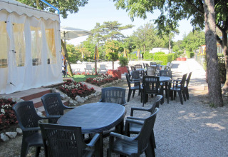 Udendørs spiseområde med plastikborde og stole på Camping Village Mare Pineta i Friuli-Venezia Giulia, Italien.