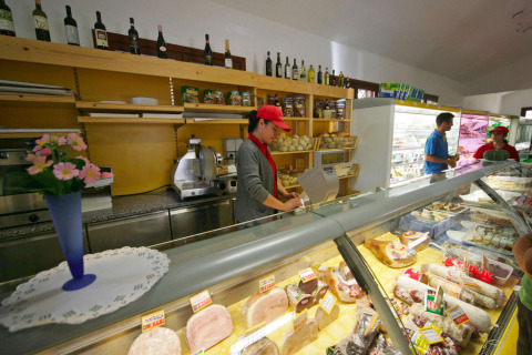 Vista interior de una tienda de delicatessen con personal, en Camping Village Mare Pineta, Italia.