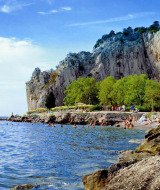 Playa rocosa cerca de Sistiana en Friuli-Venezia Giulia, Italia, con bañistas disfrutando el paisaje.