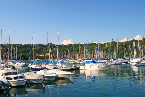 Barche ormeggiate al porto del Camping Village Mare Pineta, Friuli-Venezia Giulia, Italia, con colline verdi sullo sfondo.
