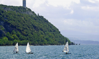 Veleros navegando junto a una ladera con torre cerca de Sistiana, Friuli-Venezia Giulia, Italia.