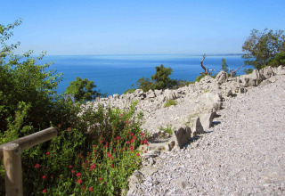 Vista sul mare azzurro e paesaggio roccioso da un sentiero al Camping Village Mare Pineta, Friuli Venezia Giulia.