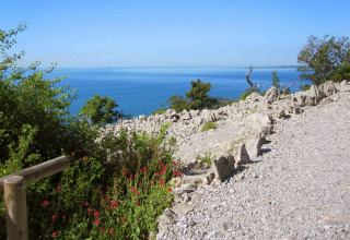 Udsigt over det blå hav og klipper fra en sti ved Camping Village Mare Pineta i Friuli-Venezia Giulia, Italien.