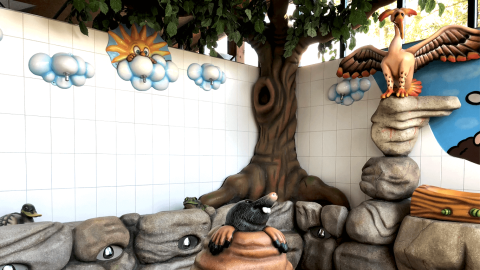 Parque infantil con figuras de animales, arte mural colorido y rocas artificiales en Vakantiepark De Luttenberg, Overijssel.