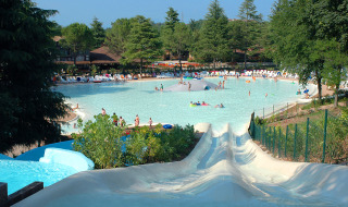 Gran piscina con toboganes de agua y personas, rodeada de árboles en Altomincio Family Park, Lombardía.