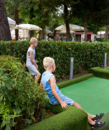 Familia jugando mini golf en Altomincio Family Park, un parque vacacional en Lombardía, Italia.