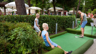 Familia jugando mini golf en Altomincio Family Park, un parque vacacional en Lombardía, Italia.