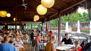 Ambiente animado de restaurante familiar en Altomincio Family Park, Lombardía, Italia, con familias cenando.