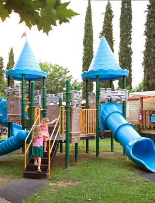 Niños juegan en un colorido parque infantil con toboganes en Altomincio Family Park, Lombardía, Italia.