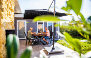 Ældre par nyder frokost under en parasol på terrassen i Resort Mooi Bemelen, Limburg, Holland.