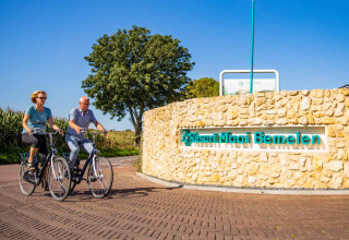 Deux personnes font du vélo près de l'entrée du Resort Mooi Bemelen, parc de vacances à Limbourg, Pays-Bas.