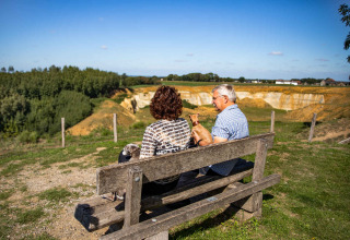 Twee personen zitten op een bankje bij Resort Mooi Bemelen in Limburg, Nederland, en genieten van het landschap.