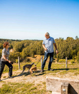 Dos personas pasean con dos perros y disfrutan de la naturaleza en Resort Mooi Bemelen, Limburg, Países Bajos.